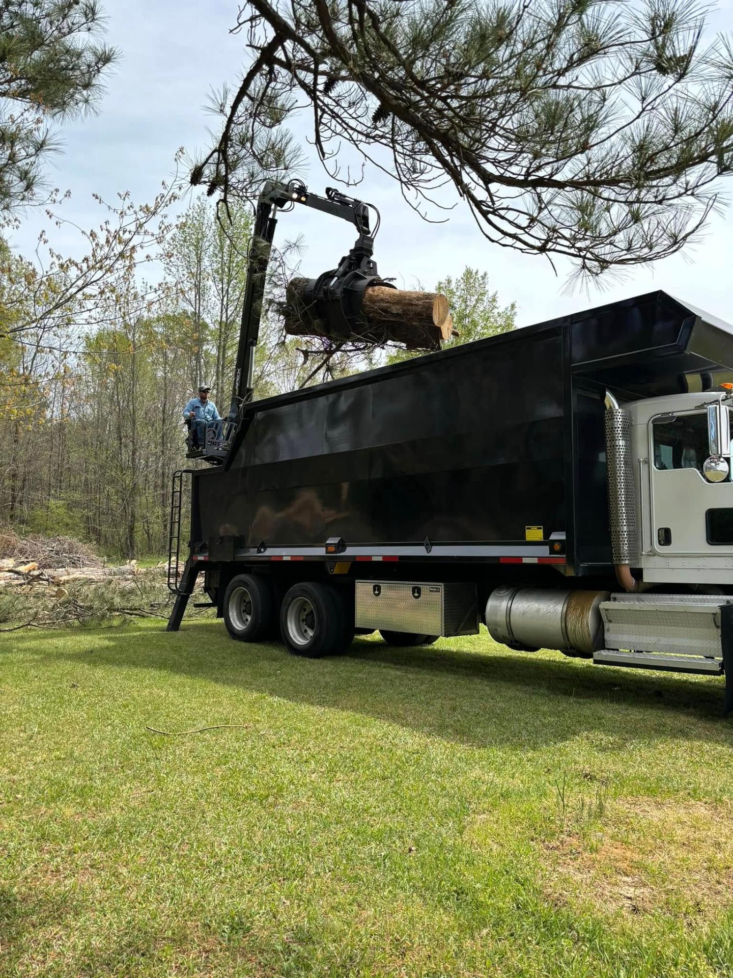 All-American Tree Service grapple truck loading a freshly cut log on a commercial job site